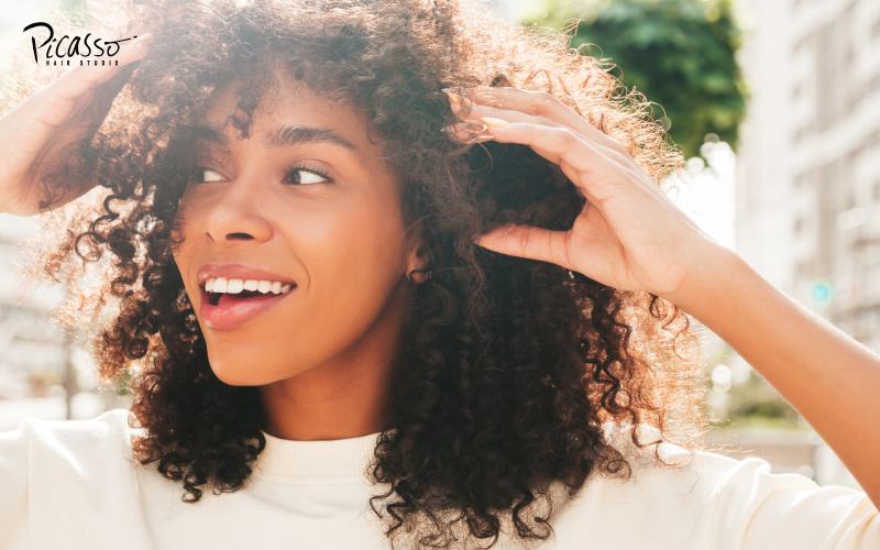 Happy woman touching her naturally curly hair.