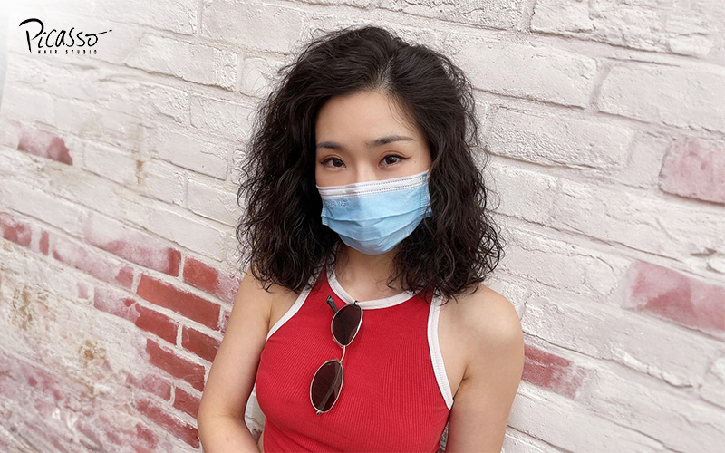 Woman in mask showcasing her spiral permed hairstyle from Picasso Hair Studio.
